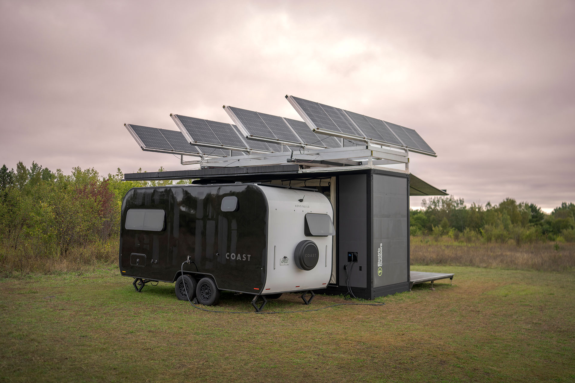A moody image of an RV parked next to a large camping structure with solar panels on the roof