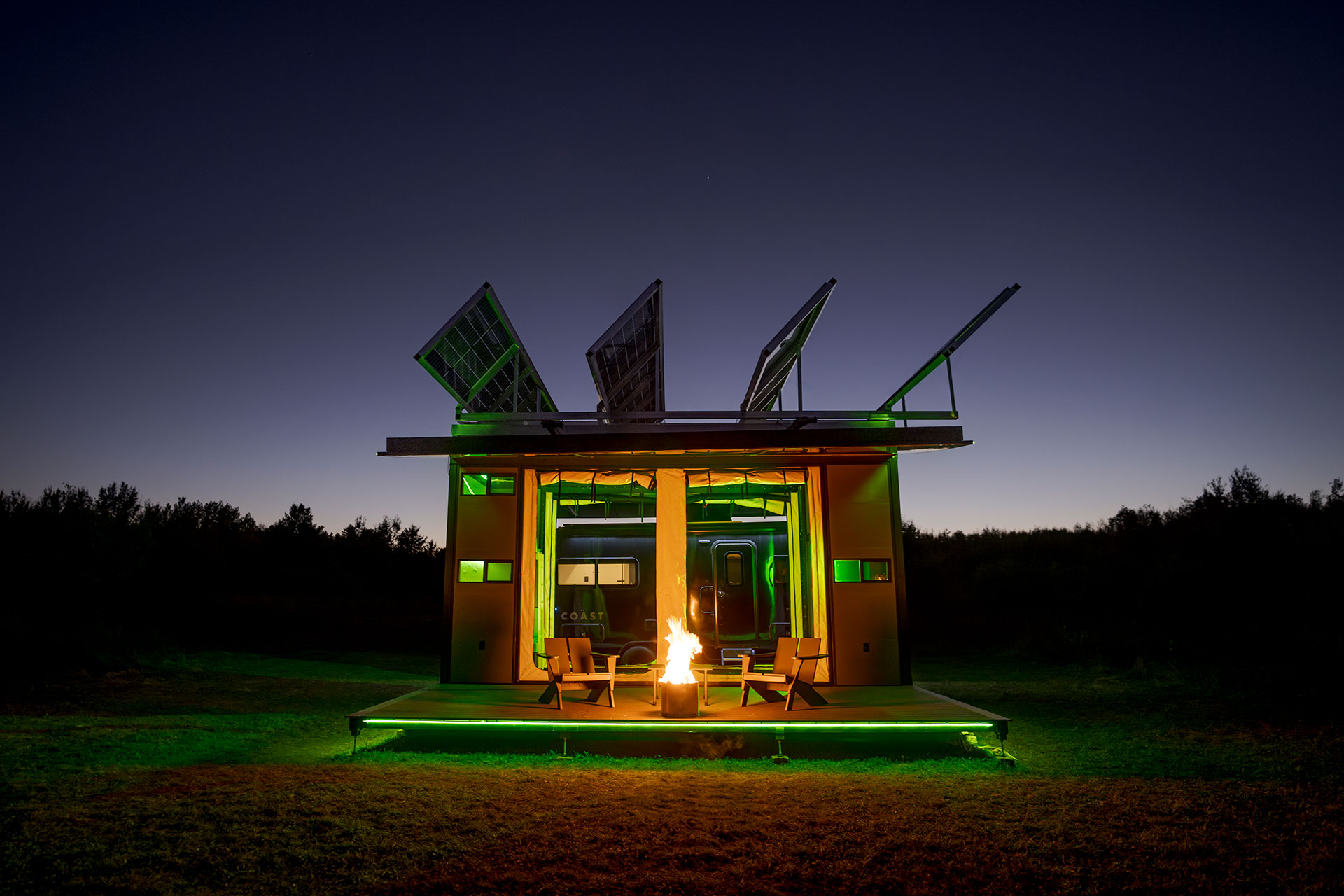 A large camping structure at night, featuring a fireplace and green lighting