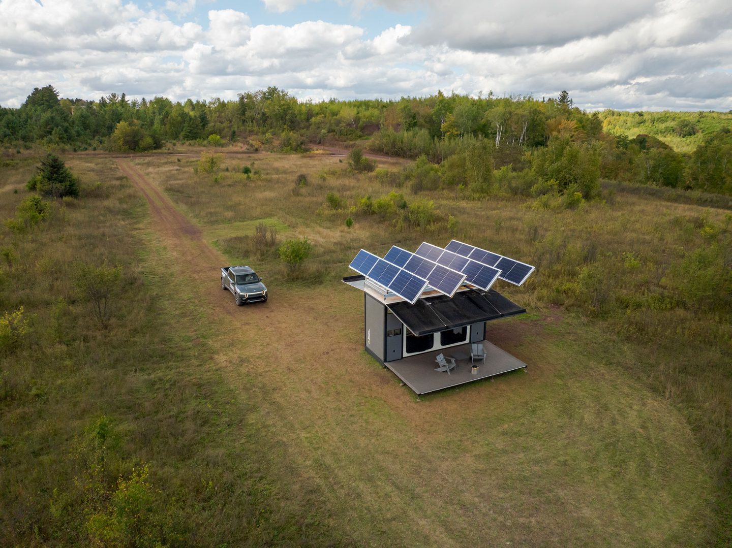 A large camping structure with solar panels on the roof set in a green, forested area