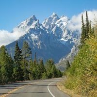A winding road with snow-covered mountains rising up in the background