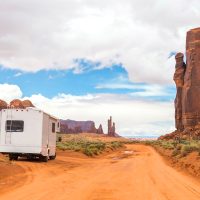 A motorhome parked on the side of a desert road surrounded by red rock landscape
