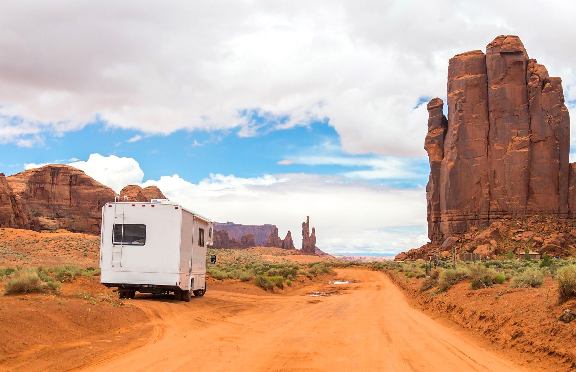 A motorhome parked on the side of a desert road surrounded by red rock landscape