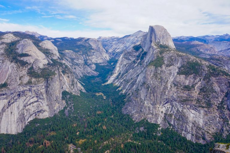An aerial photo of a lush. green valley surrounded by towering granite cliffs
