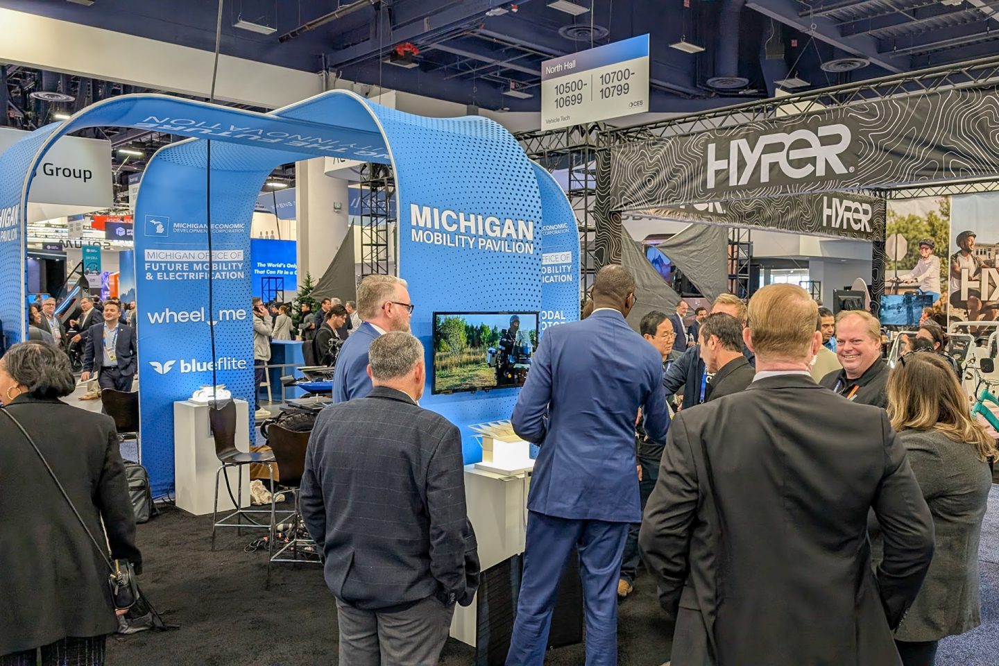 Several people in suits stand around a booth at a trade show