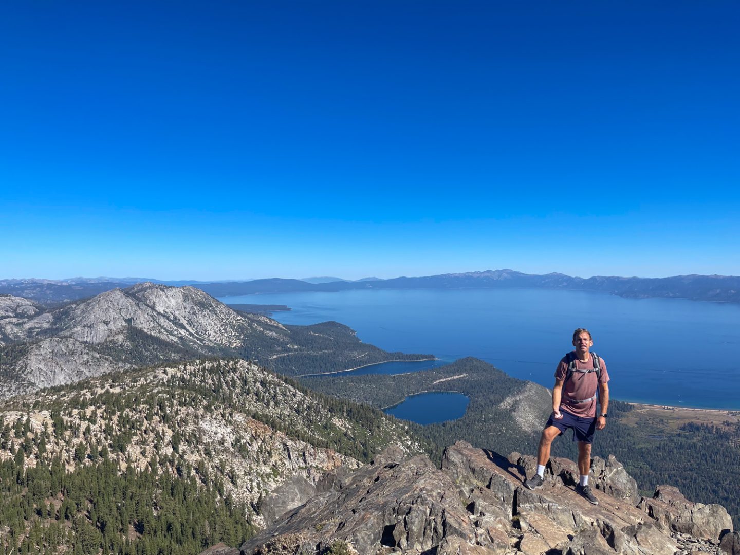 Man standing on a tall cliff with a lake behind him