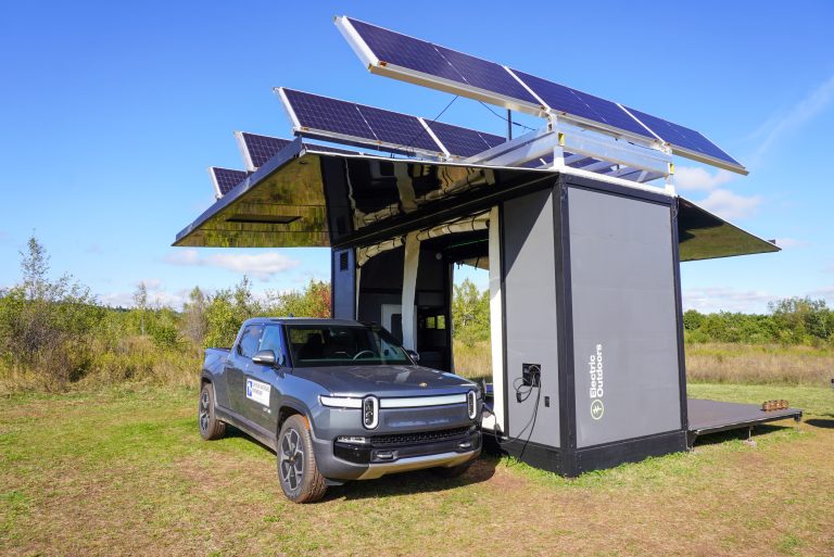 A large solar powered camping structure with a Rivian plugged into an EV charger