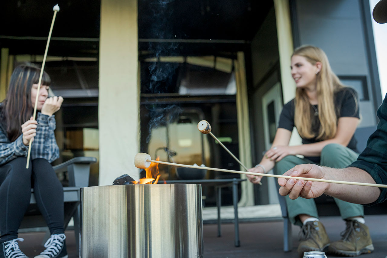 Three people roasting marshmallows over a campfire